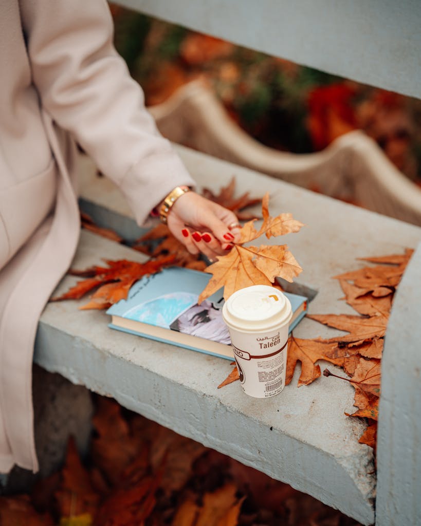 Woman Sitting on a Bench with a Book and Coffee